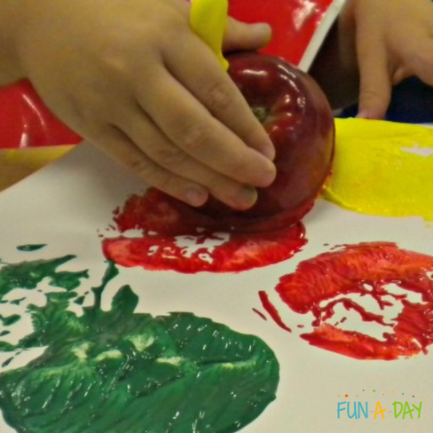 preschooler painting with apples