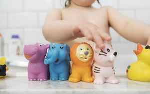 Toddler lining up animal bath toys next to a tub