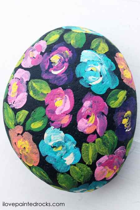 Bright colored loose florals painted on a black rock perfect tutorial for beginners.