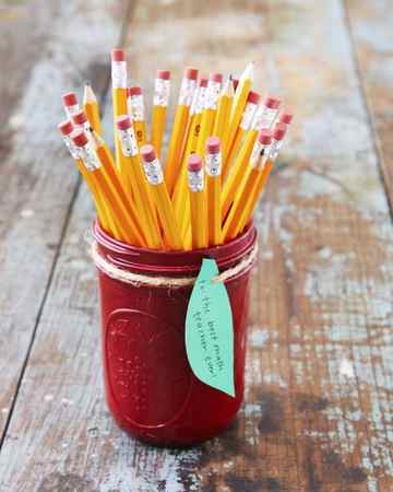 a mason jar painted red filled with pencils and an apple leaf shaped tag attached