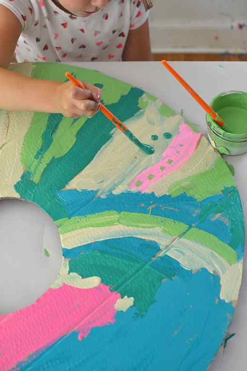 Mixing paint colors using tempera paints to paint giant cardboard donuts.