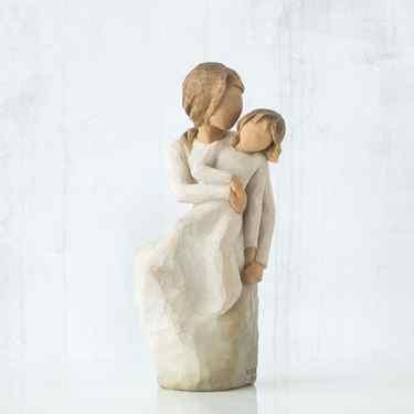 Faceless woman figurine holding young girl figurine in her arms - both in white dresses