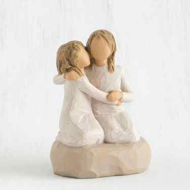 Two blonde faceless girls wearing white dresses hugging another on rock figurine