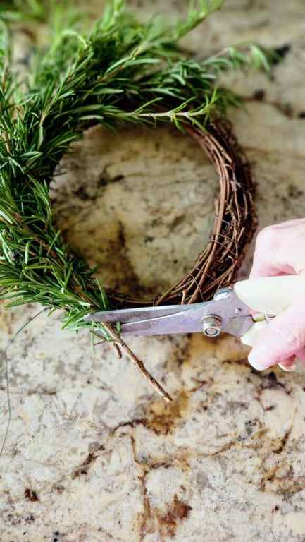 using wire cutters, clipping the ends of the rosemary sprigs that are too long