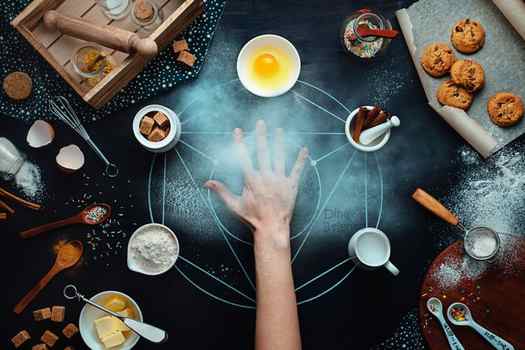 Overhead shot of an outstretched hand in the middle of a fun food photography arrangement on dark background - still life photography ideas. 