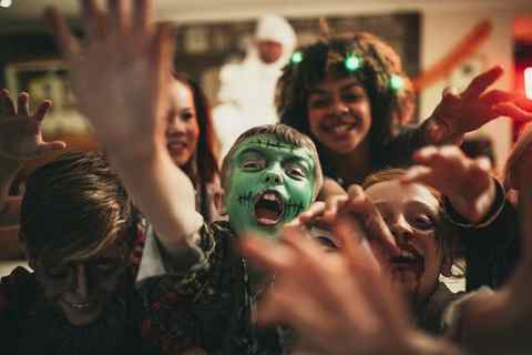 group of young friends dressed in costumes reaching out towards the camera like zombies