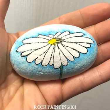 Create a watercolor effect with Posca paint pens or regular acrylic paints. This easy tutorial will walk you through a fun technique by painting a daisy rock. Watch the video and find out how easy this process is. It