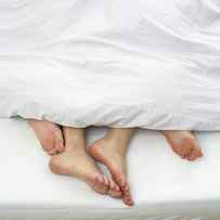 Bare Feet Of Couple In Bed by Stock4b-royaltyfree