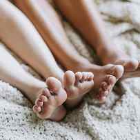 Cropped View Of Couples Legs Lying Down On Bed by Lena Mirisola