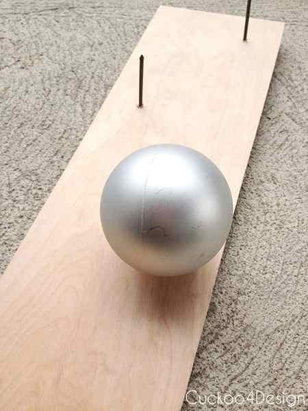 Christmas ball ornament stuck on a nail through wooden board for painting