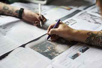 person holding marker pen writing on newspaper