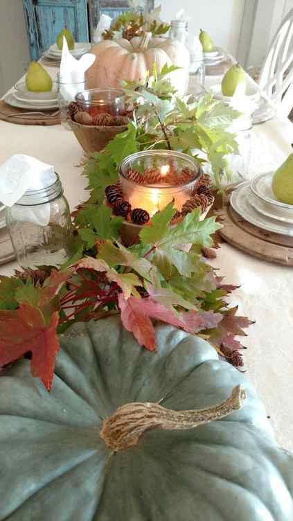 fall table decor with heirloom pumpkins, fall leaves, candle lanterns with pinecones is very cozy