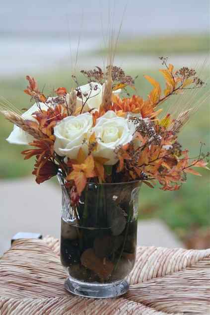 a vase with pebbles and rocks, dried fall leaves, white roses, wheat looks very chic and very natural