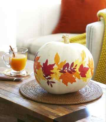 a cool pumpkin centerpiece with bright fall leaves attached is an amazing fall decoration